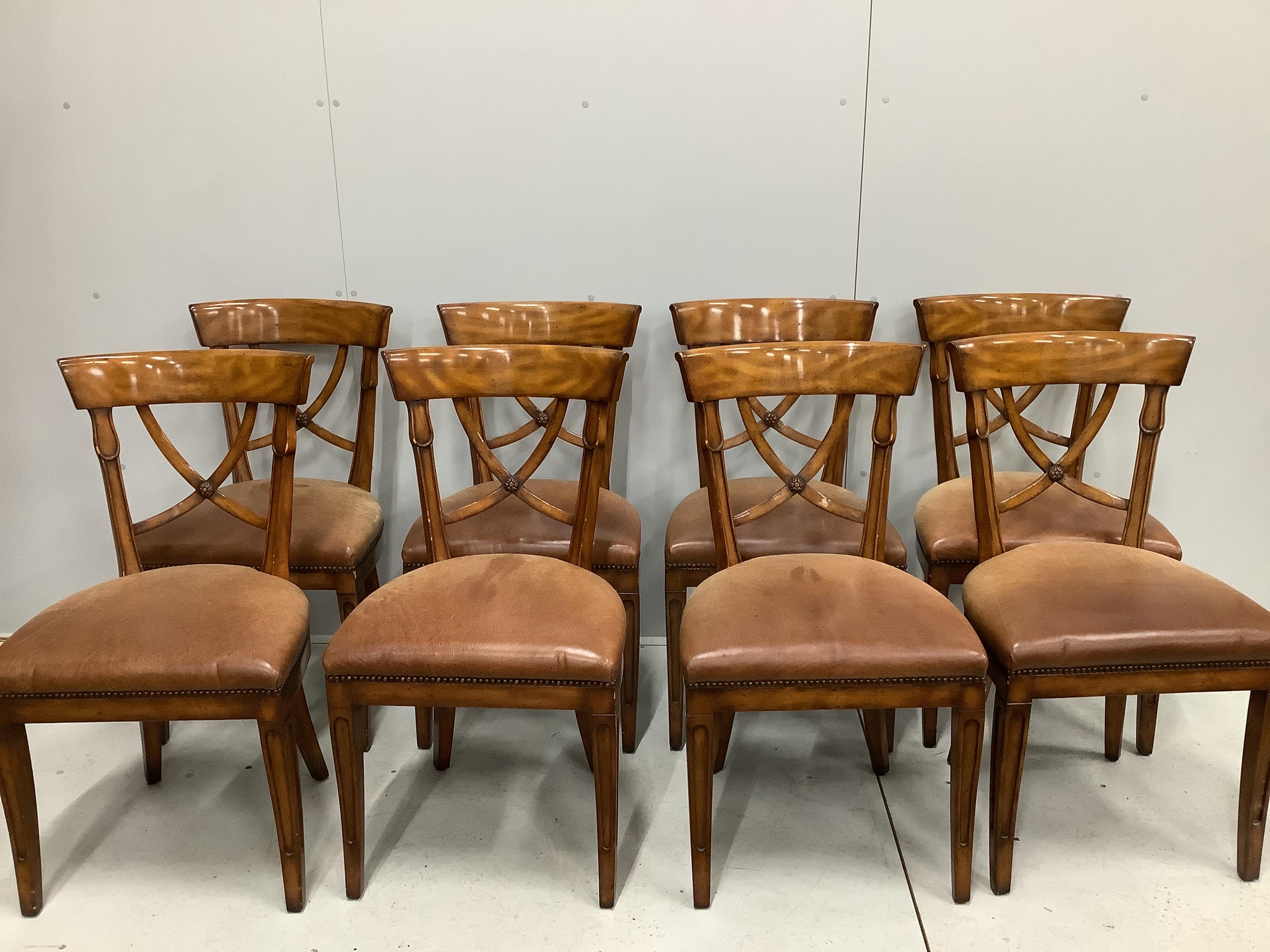 A reproduction George III style circular mahogany extending dining table with detachable segmental outer ring and eight Empire style cherry dining chairs with tan leather seats, table 142cm diameter, 202cm diameter exten